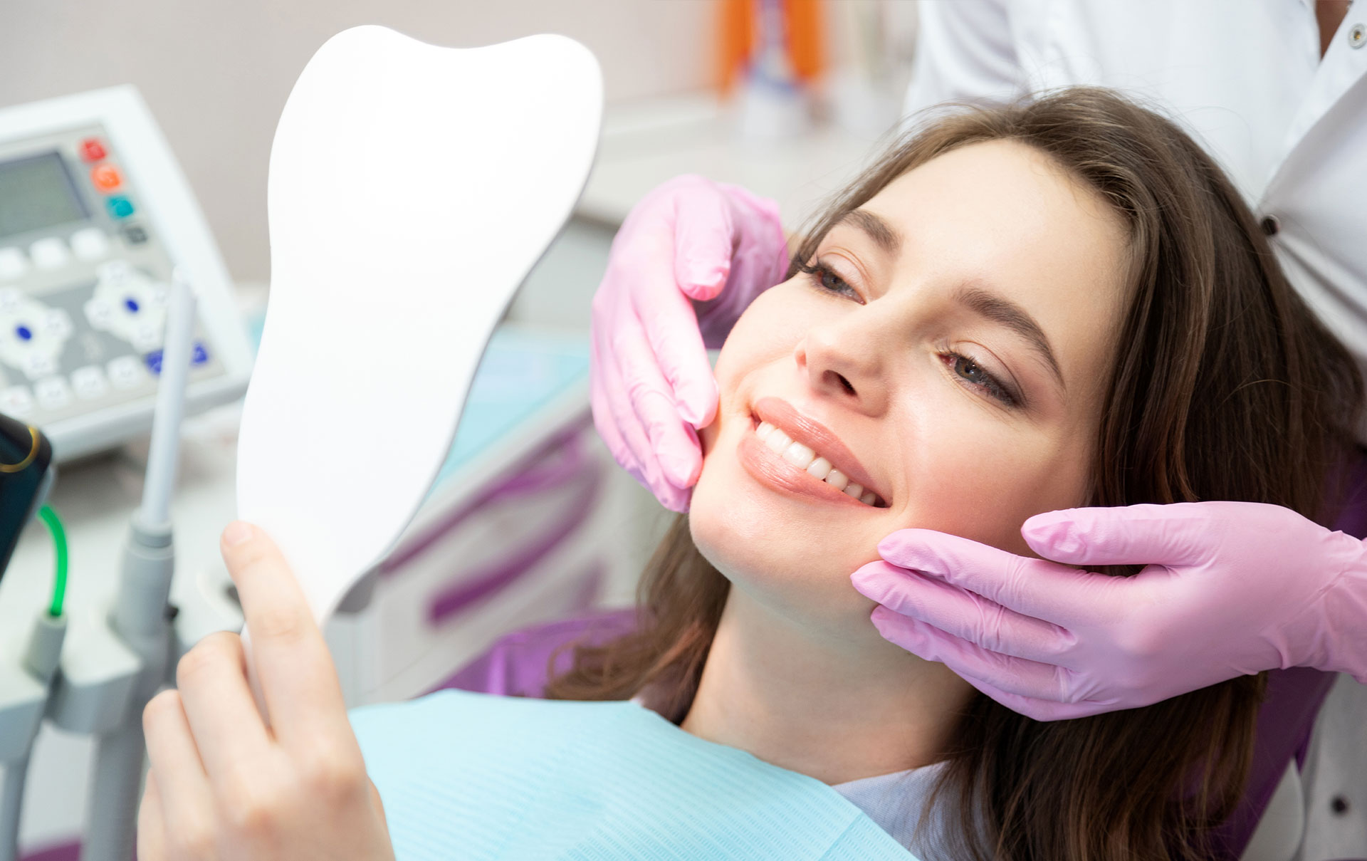 Woman sitting in dental chair receiving oral care with smiling expression.