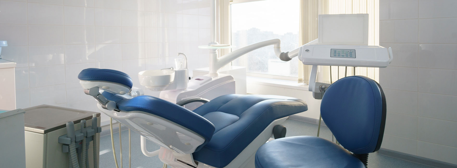 The image shows a modern dental office with a clean and sterile appearance, featuring dental chairs, a dental treatment table, and other equipment typically found in such settings.
