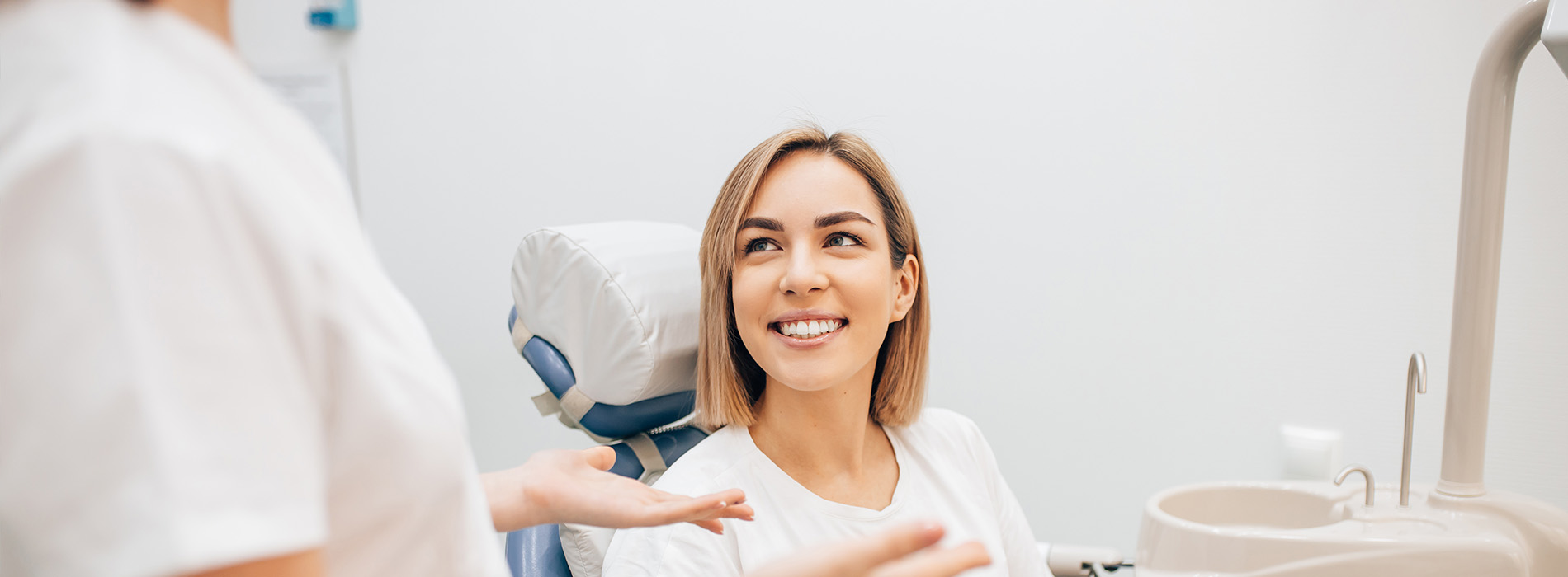 A woman sitting in a dental chair receiving treatment from a dentist.
