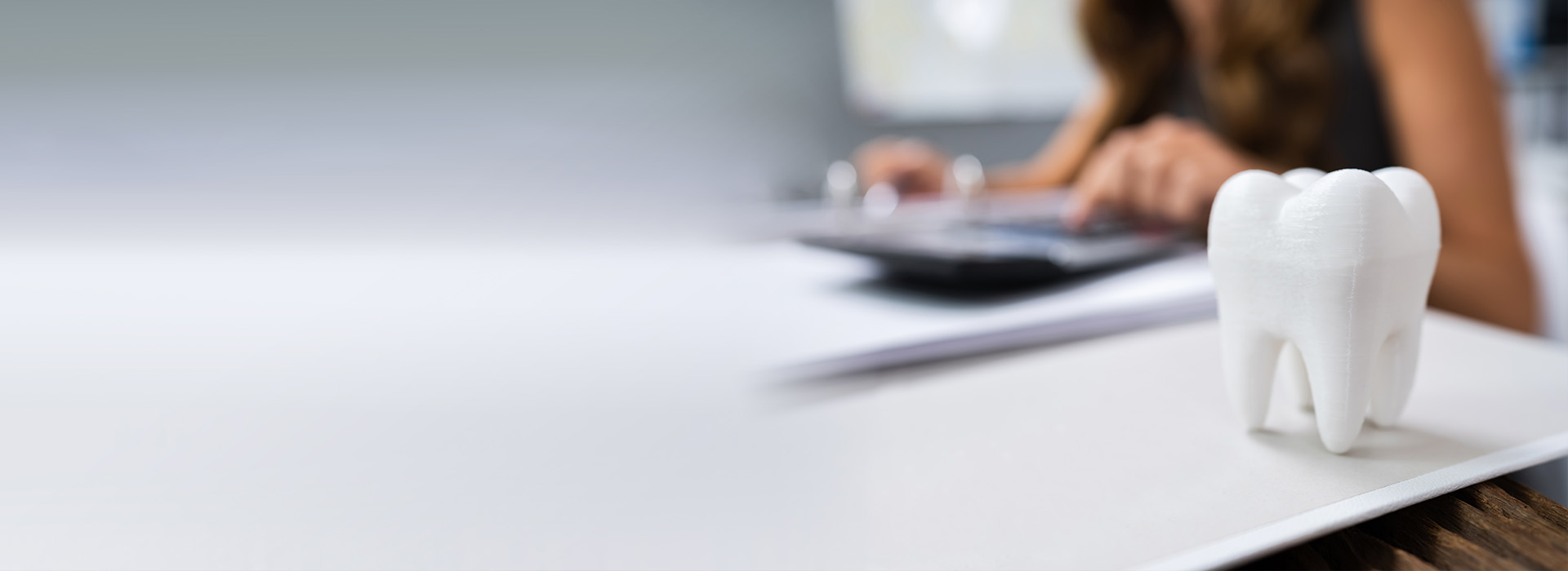 The image shows a person sitting at a desk with paperwork, using a laptop, with a clear focus on the task at hand, while a playful toothbrush holder adds a touch of whimsy to the workspace.