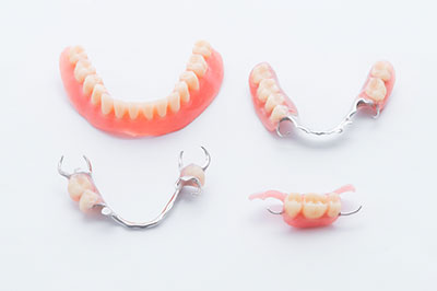 The image shows a collection of dental implants with teeth attachments displayed on a white background.