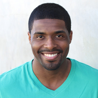 A man and woman are smiling at the camera while posing closely together for a portrait photo.