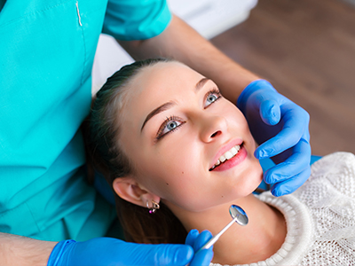 The image shows a person sitting in a dental chair being attended to by a dentist.